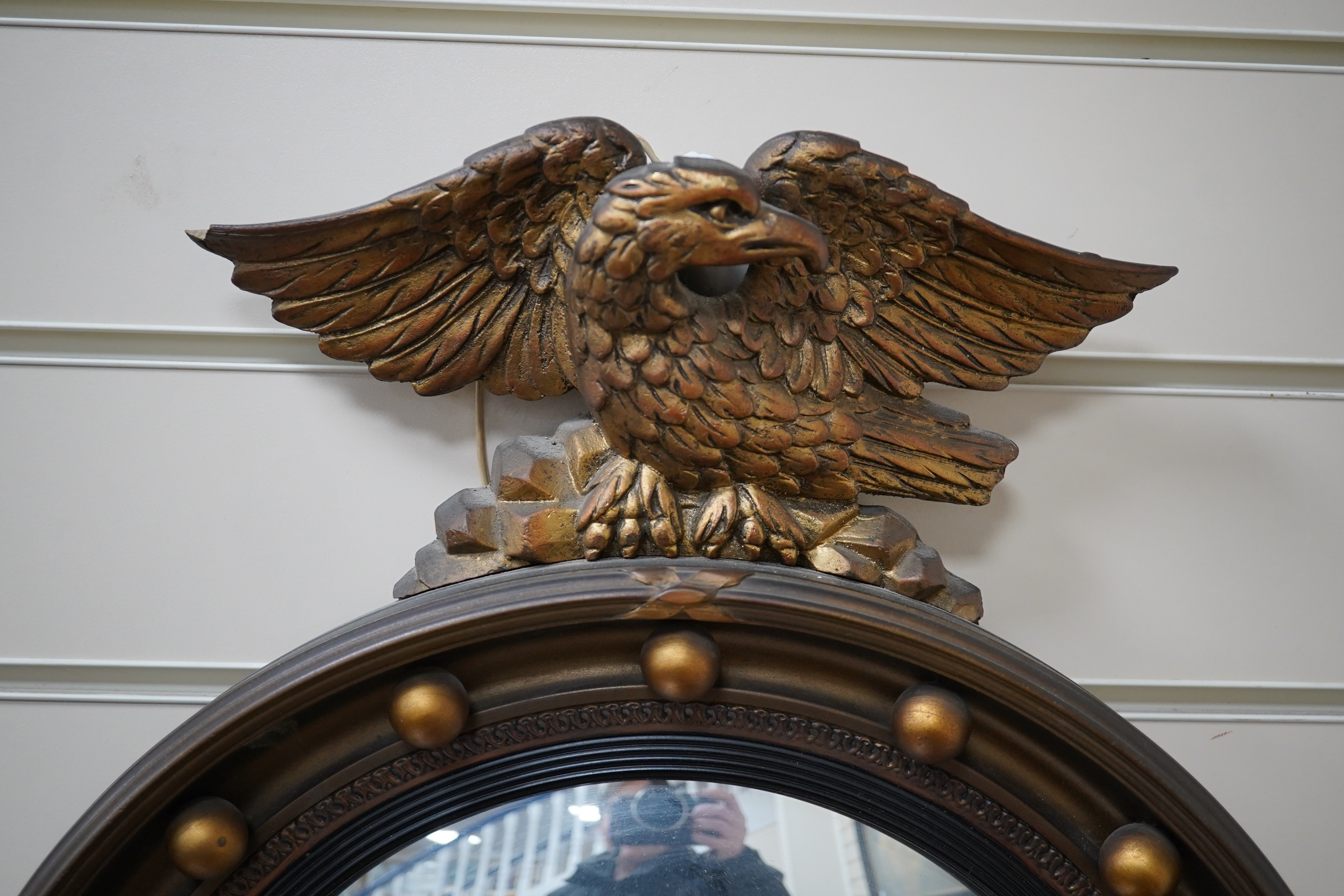 A circular convex gilt girandole mirror with carved eagle surmount, 62cm high. Condition - wing tip of eagle broken, gilt of frame scratched near the bottom, faux candle cover broken and the other missing